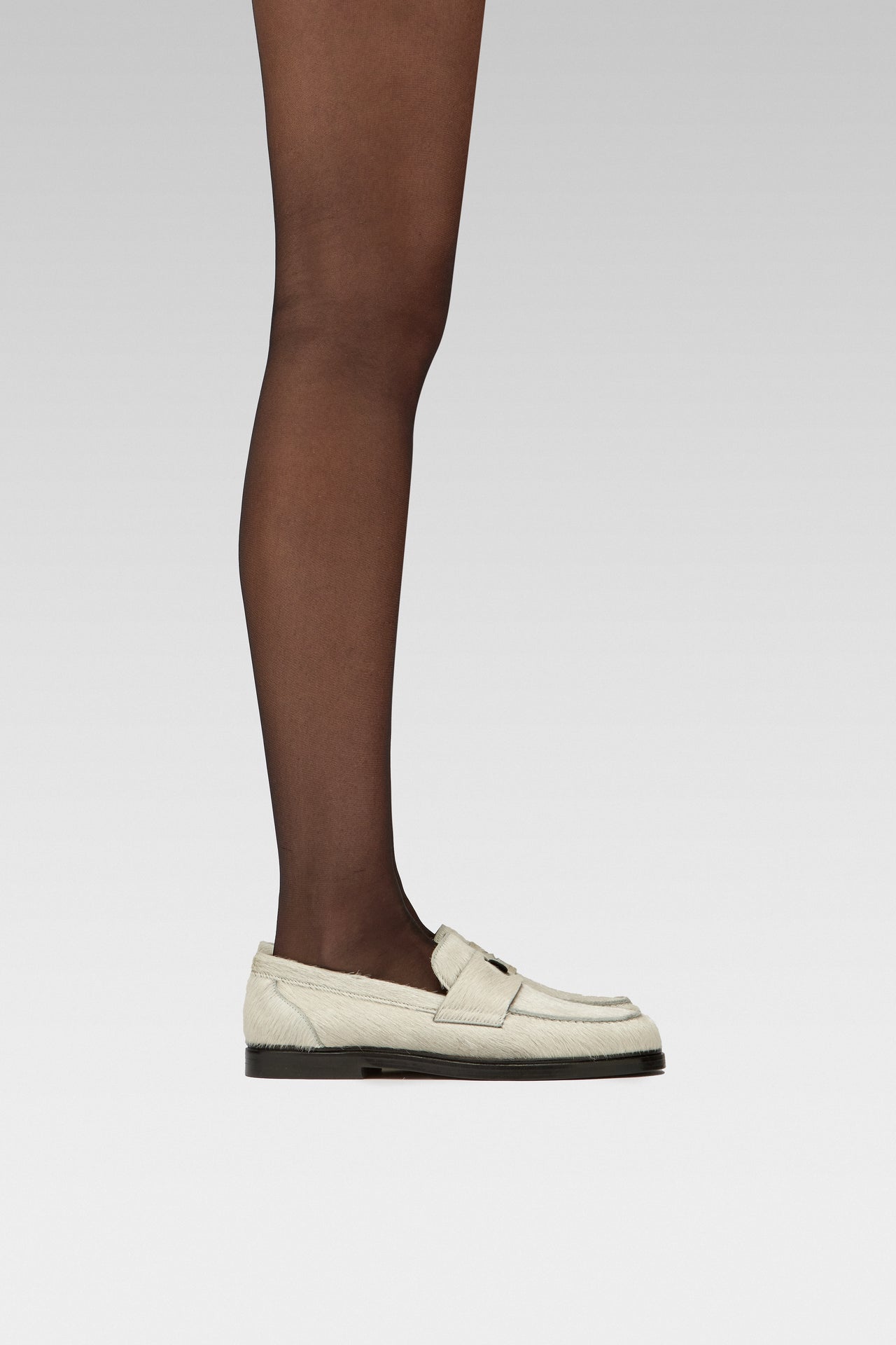 EDLA Eclipse tights Crafted from a silky 15 denier finish, the Eclipse Tights feature a double-covered yarn, sheer body, shaped silhouette, and reinforced toe with EDLA Jupiter white loafer Crafted from soft calf hair, the Jupiter Loafer features a rounded toe and a cut-out band with moon and star details.