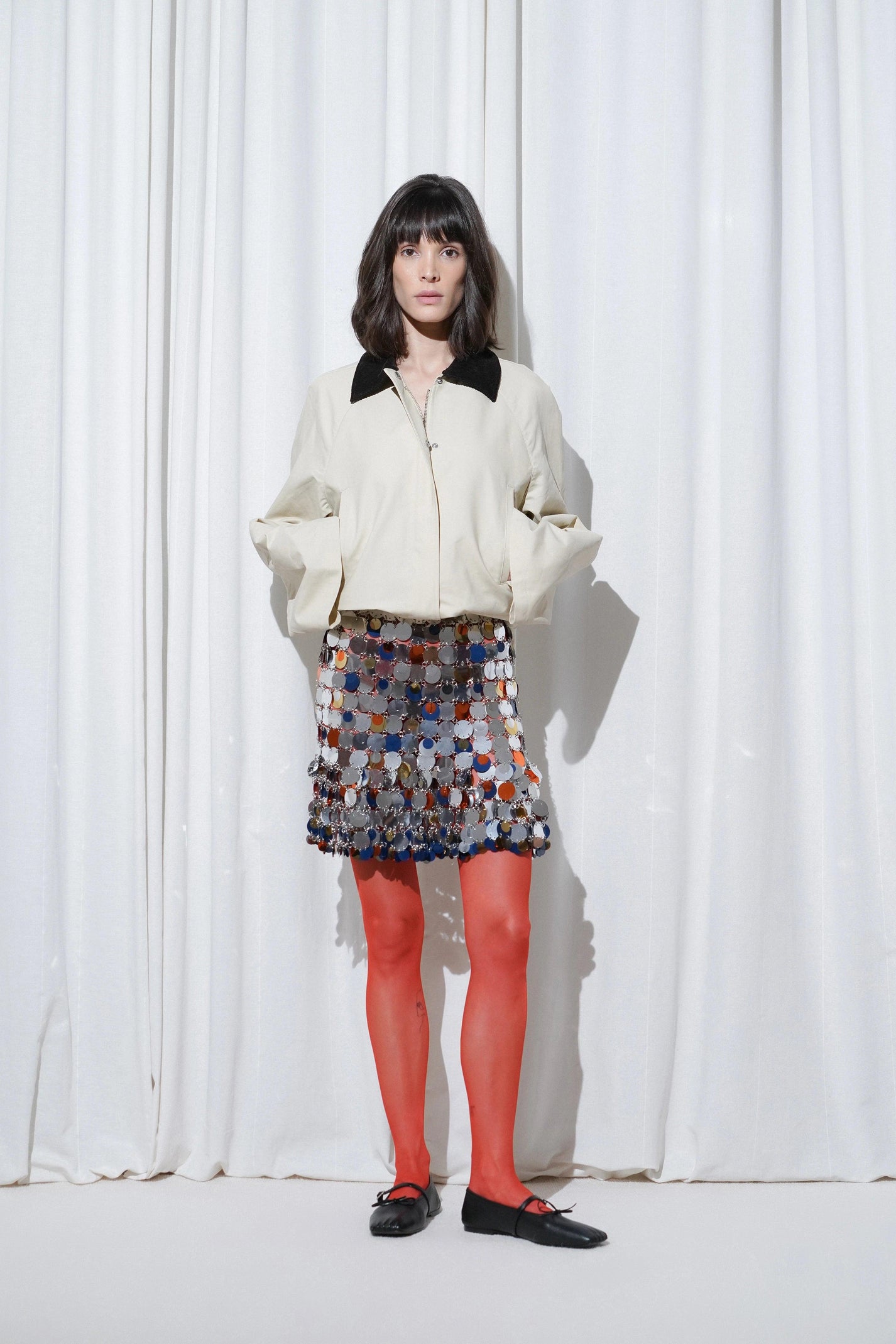 Model in party outfit with parka jacket, sequin skirt, EDLA Galaxy Red Tights, and EDLA Mars Black Ballet Flats.