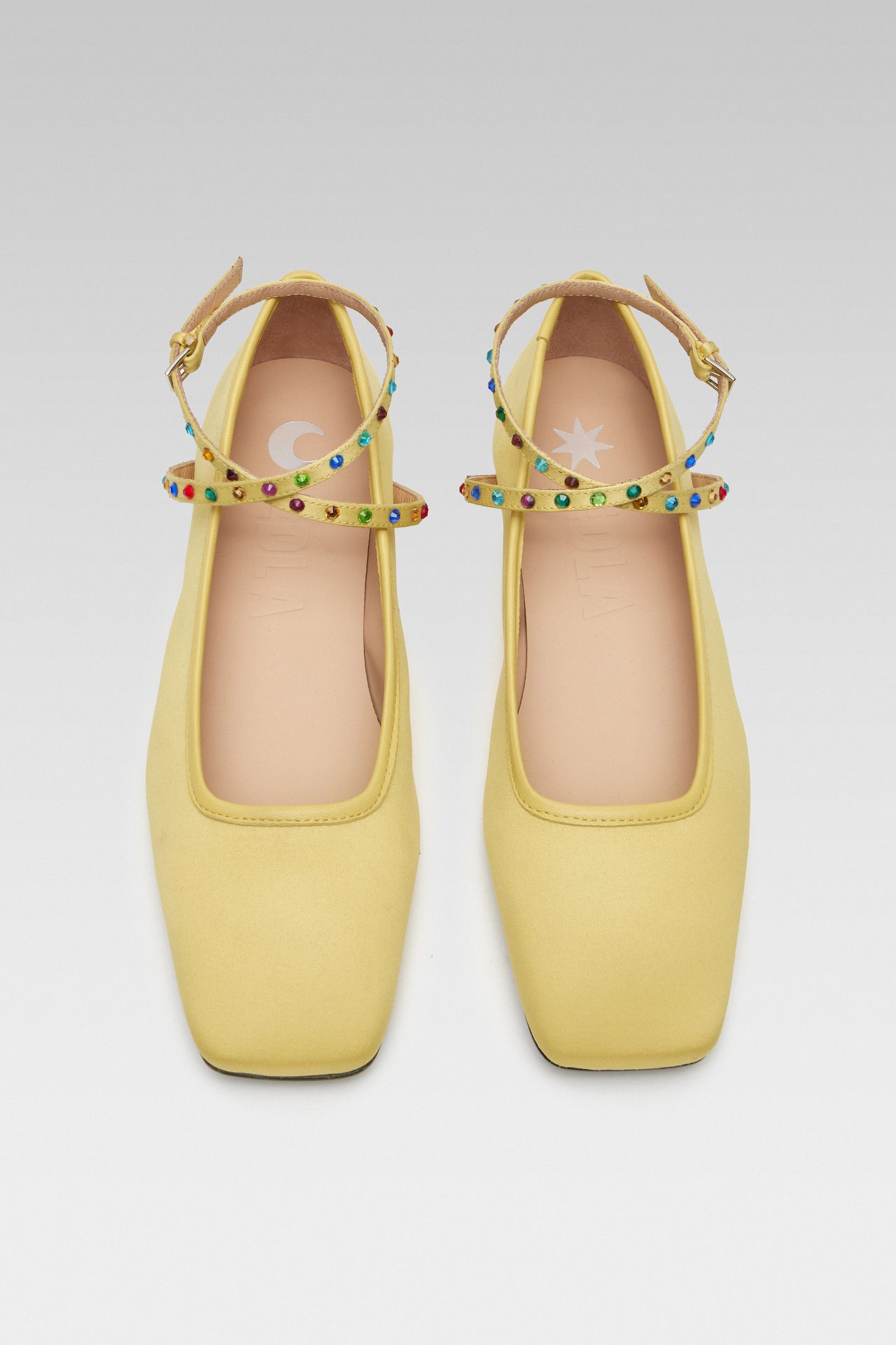 Side view of EDLA Saturn yellow ballet flats crafted from satin with ankle straps embellished with multicoloured crystals.