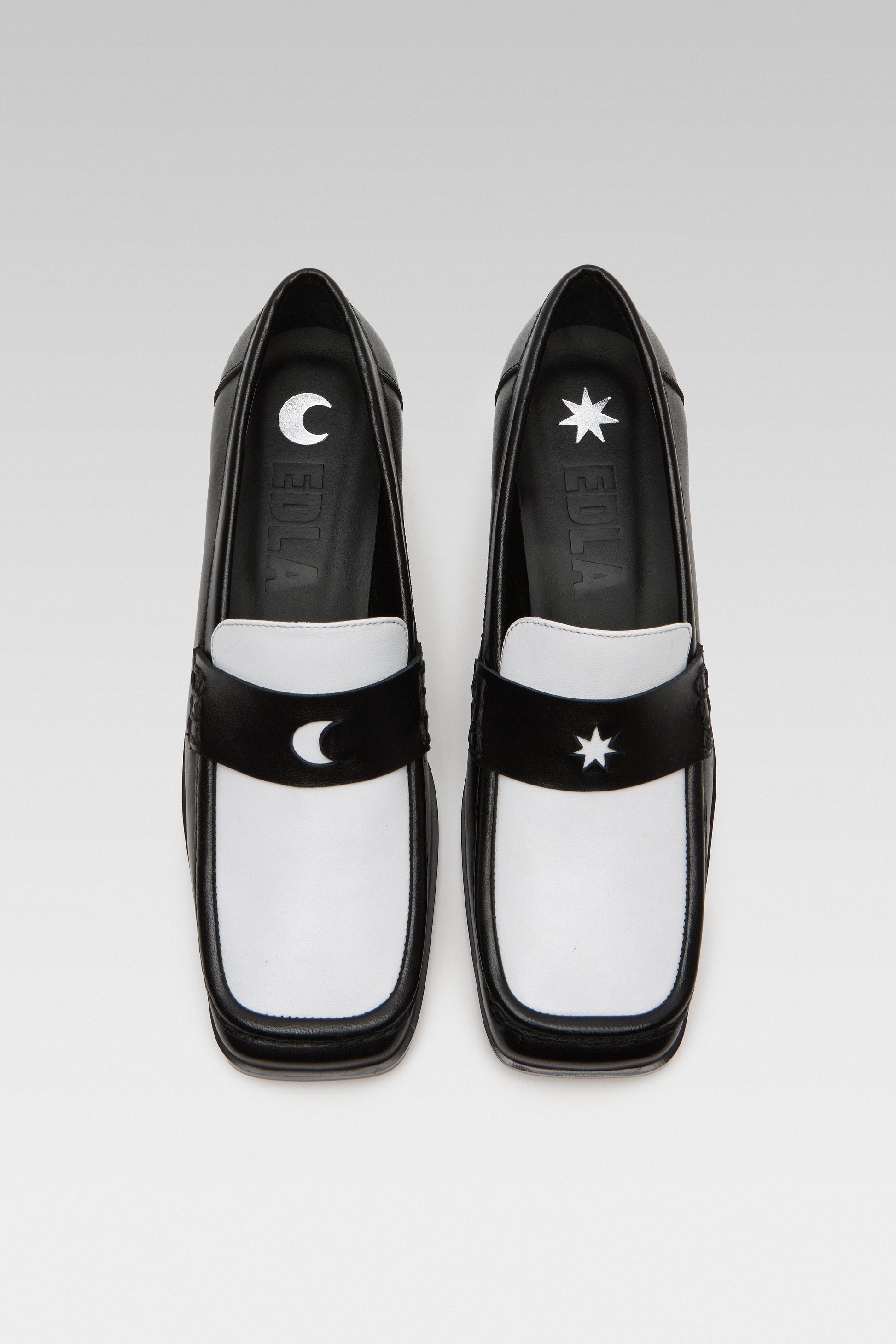 Top view of EDLA Earth black-and-white penny loafers for women crafted from leather with a square toe and star and moon inserts at the front.