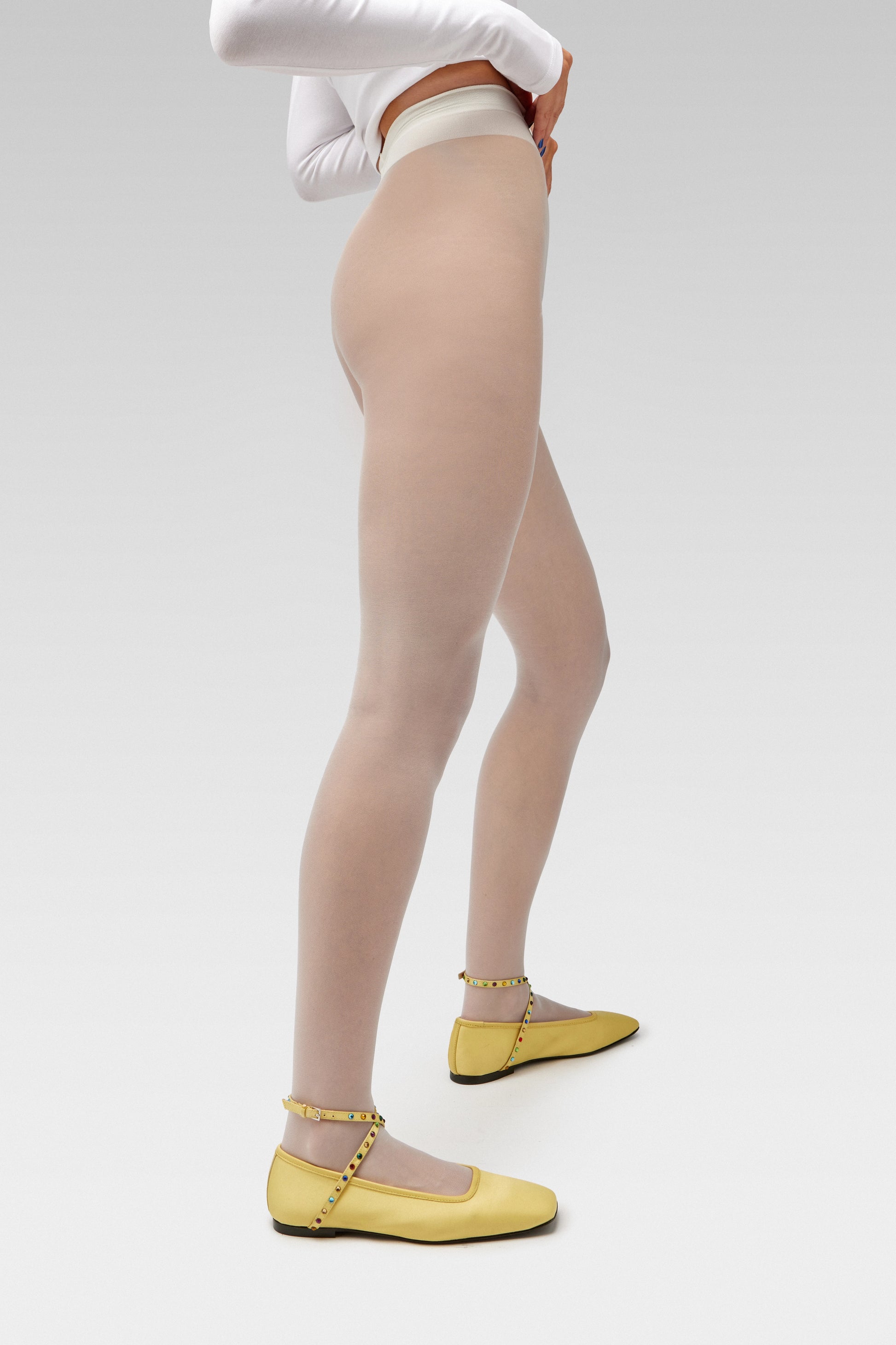 EDLA Galaxy White tights Crafted from a silky 20 denier finish, the Galaxy Tights feature a sheer body, shaped silhouette, and invisible toe together with EDLA Butter Yellow Saturn ballet flats Crafted from butter yellow satin, the Saturn Ballet Flat features multicolored crystal-embellished straps and a squared toe.