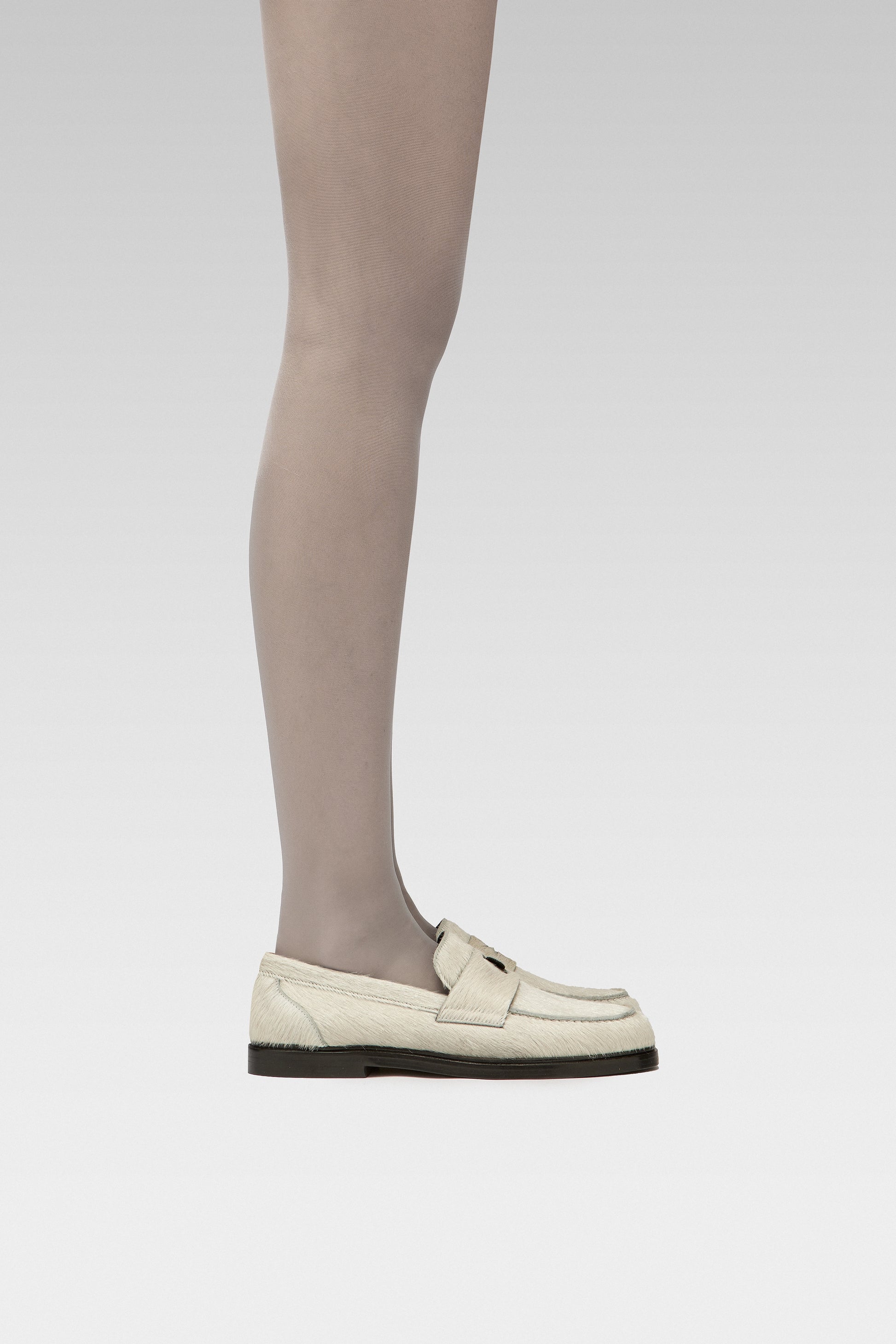 EDLA Galaxy Grey tights Crafted from a silky 20 denier finish, the Galaxy Tights feature a sheer body, shaped silhouette, and invisible toe together with EDLA Jupiter White loafers Crafted from soft calf hair, the Jupiter Loafer features a rounded toe and a cut-out band with moon and star details.