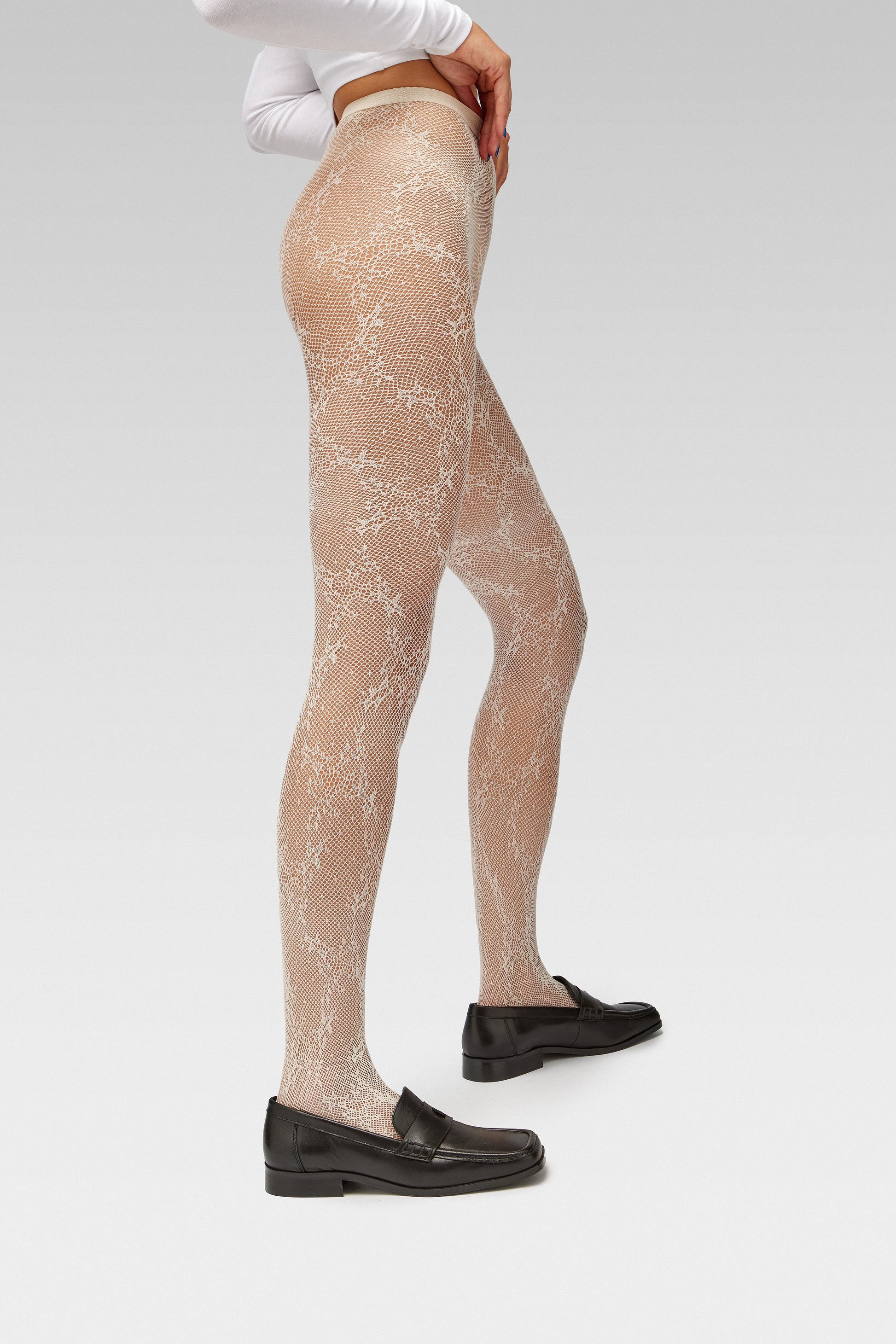 EDLA Starlight White Tights Crafted from recycled yarns, the Starlight Tights feature an intricate floral fishnet design, seamless construction, and reinforced toe for all-day comfort with EDLA Black Earth loafers Crafted from soft nappa lambskin, the Earth Loafer features a squared toe and a cut-out band with moon and star details. 