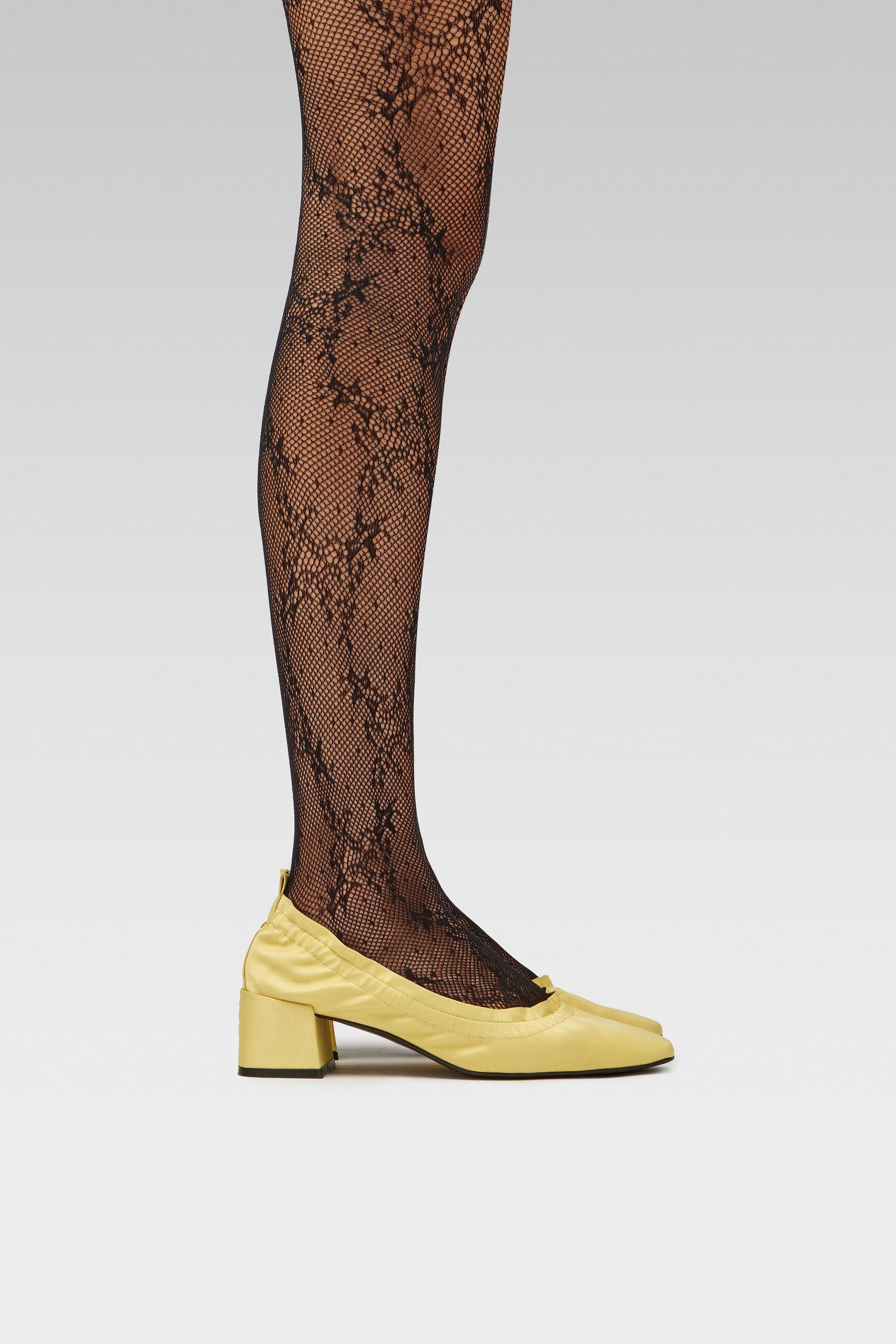 EDLA Starlight Black Tights Crafted from recycled yarns, the Starlight Tights feature an intricate floral fishnet design, seamless construction, and reinforced toe for all-day comfort with Butter Yellow Mercury Kitten Heel Crafted in satin, the Mercury Kitten Heel features a ruched edge, squared toe, and a 5cm block heel.