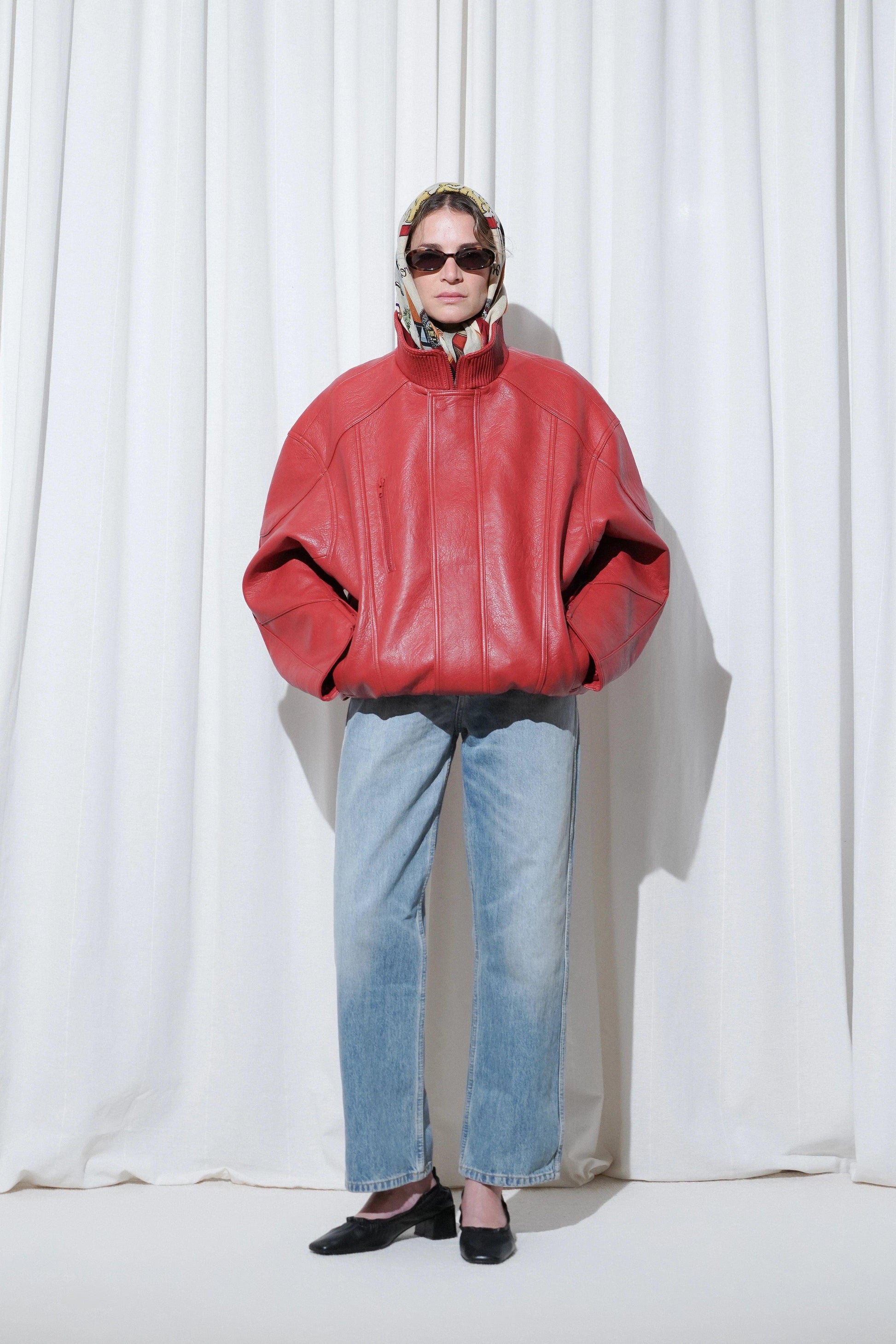 Model in a old money outfit with red oversized leather jacket, blue jeans, printed scarf, sunglasses, and EDLA Mercury Black Kitten Heels.