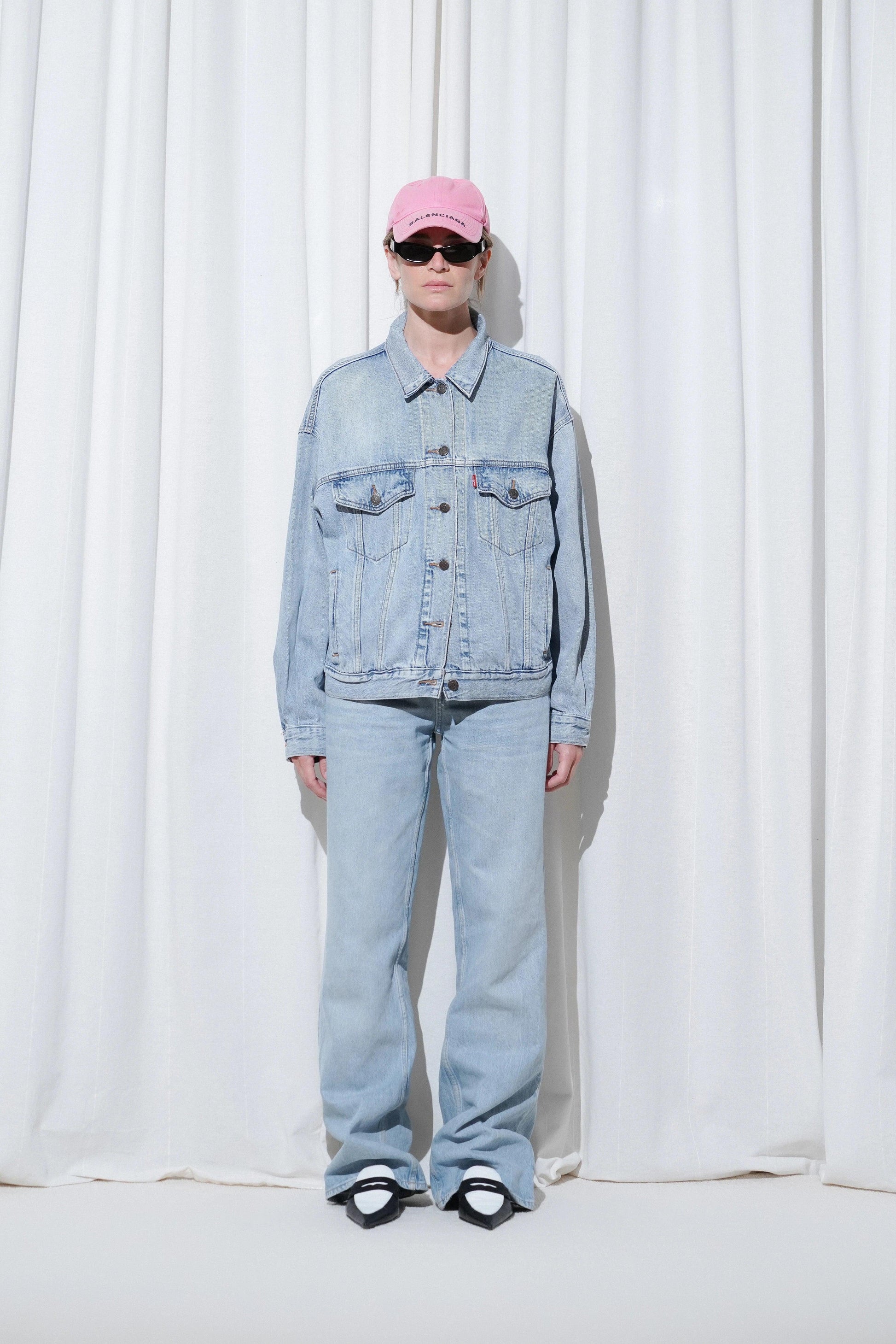 Model wearing a casual outfit with a pink cap, oversized denim jacket, light blue straight-leg jeans, and EDLA Uranus Black & White Slingbacks.