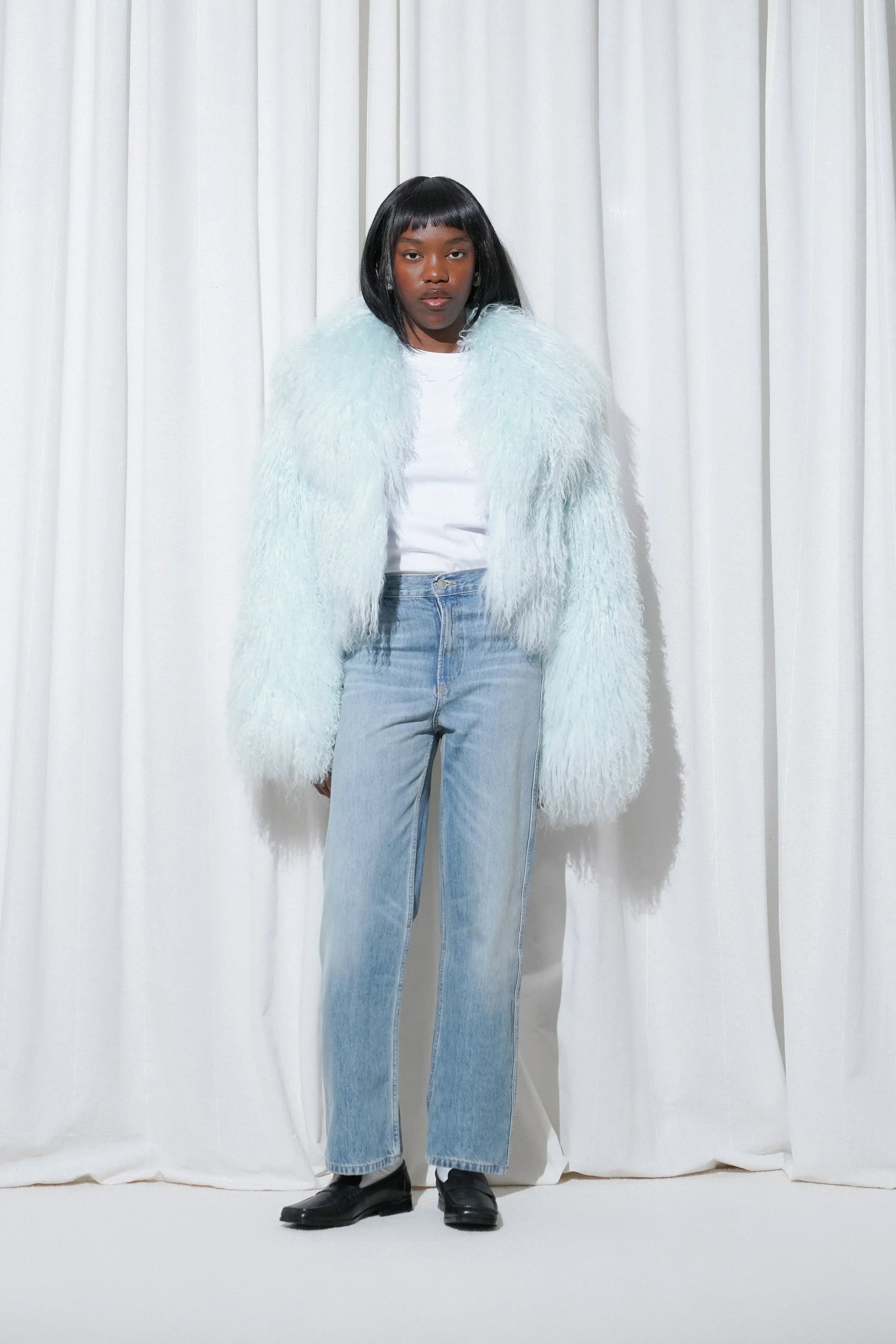 Model in a casual outfit with fluffy blue jacket, white t-shirt, blue straight-leg jeans, and EDLA Earth Black Loafers.