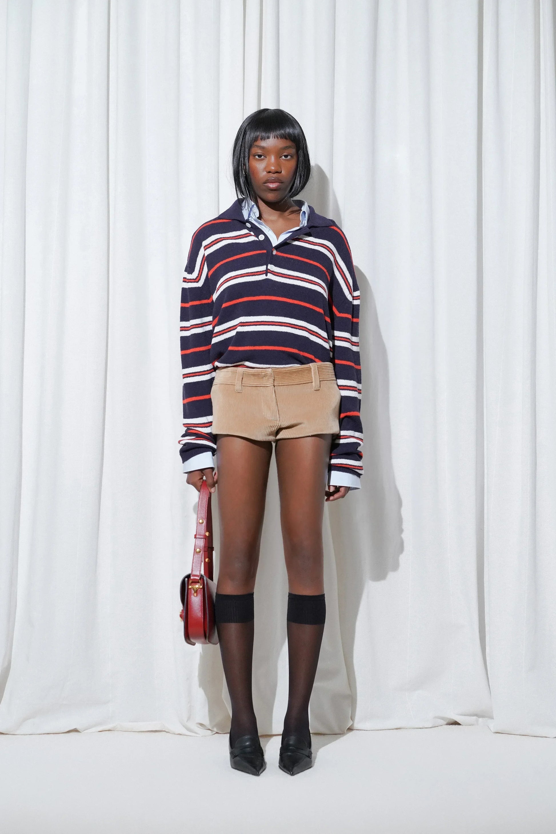 Causal look with preppy striped polo layered over shirt with corduroy shorts, EDLA Stellar Black Knee High Socks and EDLA Uranus Black Slingbacks.