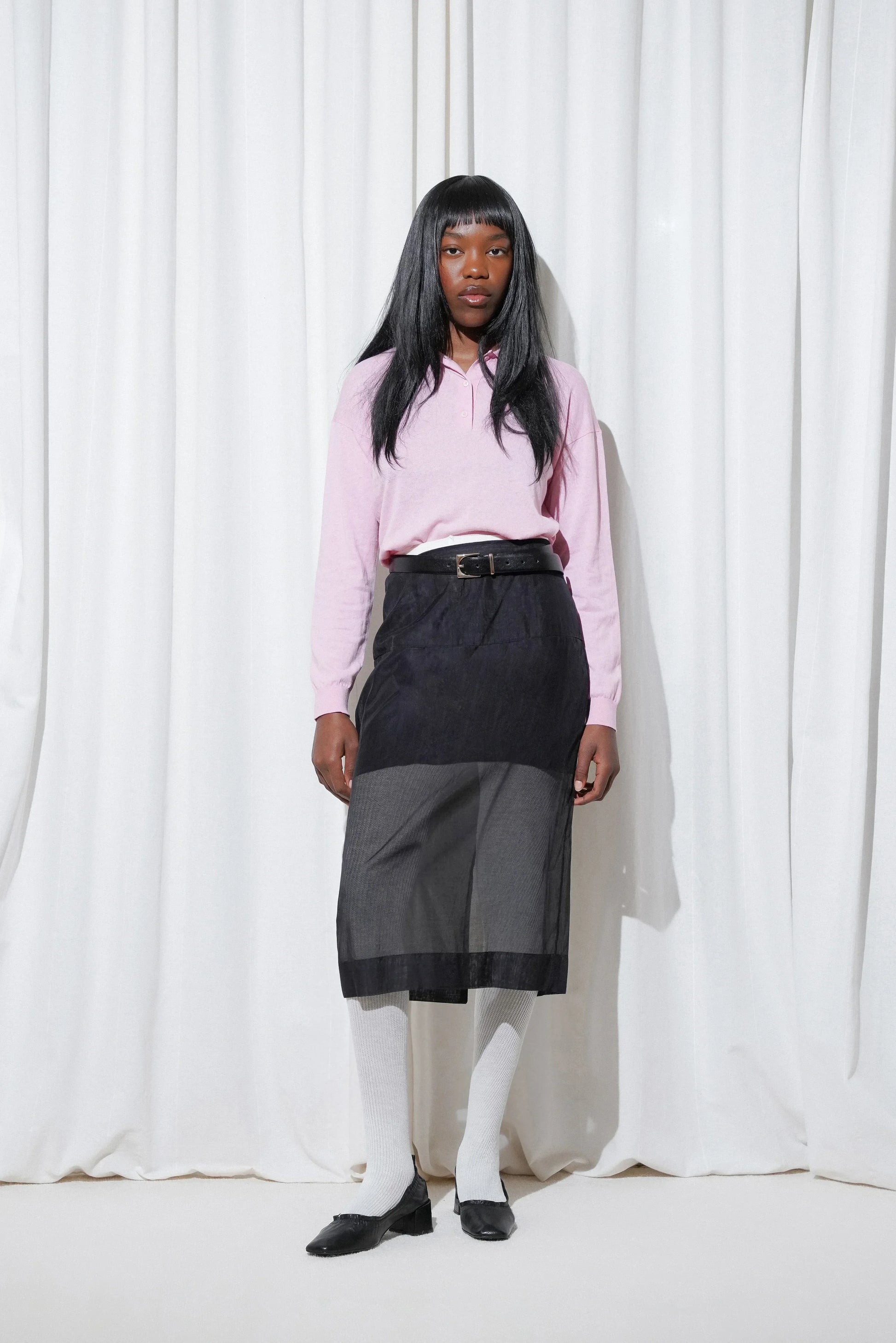 Model in a soft pink knit top tucked into a sheer overlay skirt, styled with EDLA Cosmo White Wool Ribbed Tights and EDLA Mercury Black Kitten Heels, balancing cozy textures with timeless elegance.