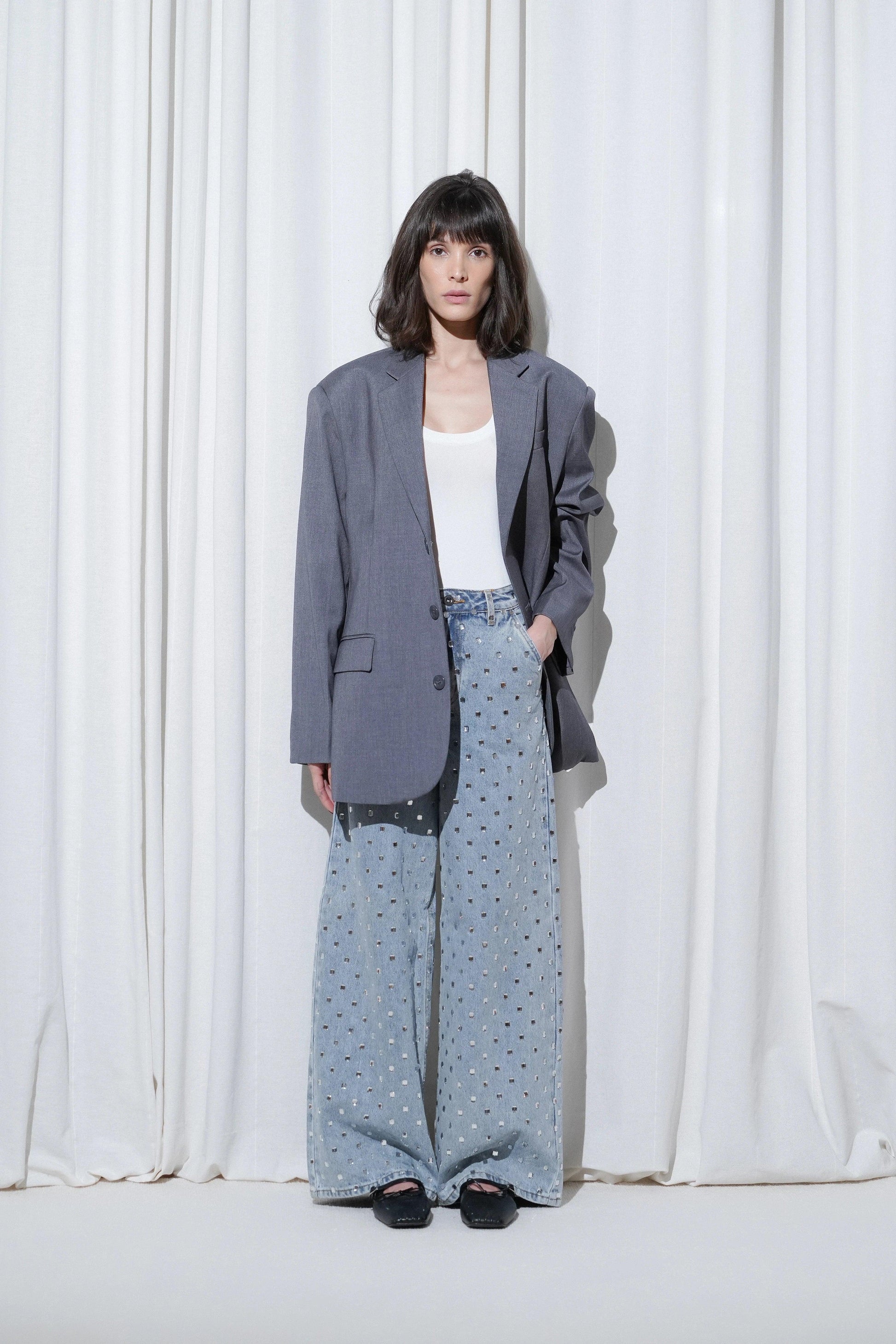 Model in a casual business outfit with grey blazer, white top, crystal wide-leg jeans, and EDLA Mars Black Ballet Flats.