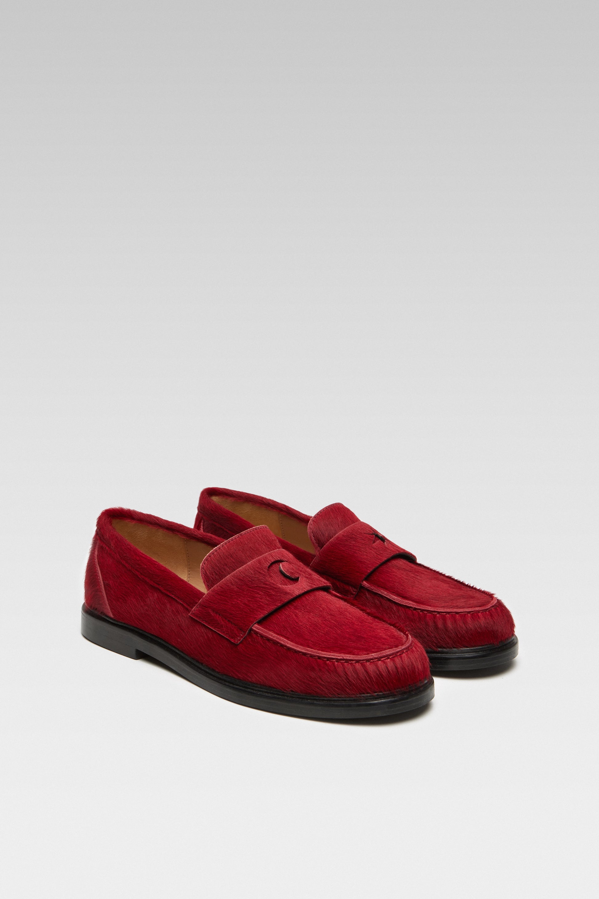 Three-quarter view of EDLA Jupiter red loafers for women crafted from calf hair with a round toe and star and moon inserts at the front.