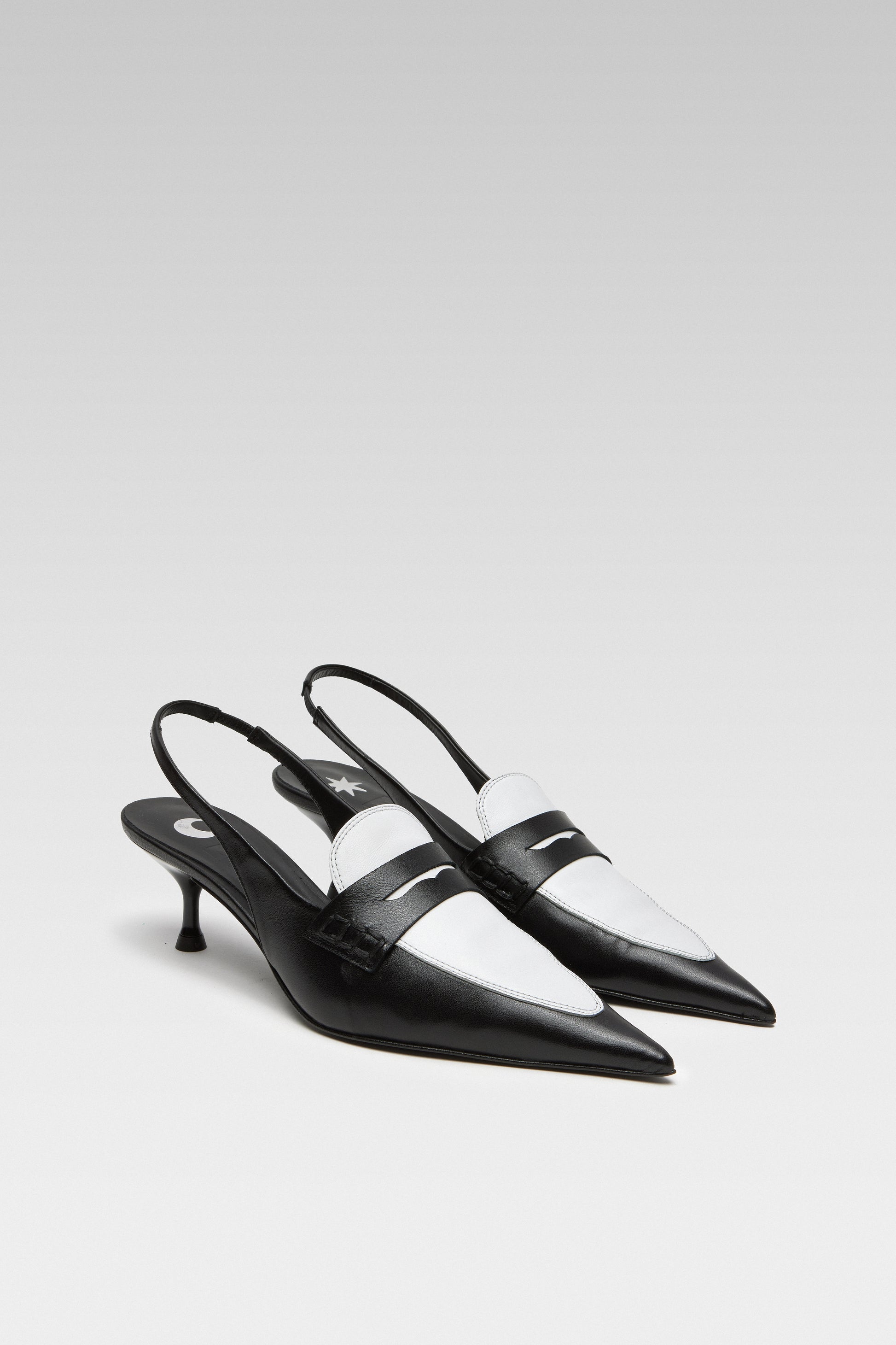 Three-quarter view of EDLA Uranus black-and-white slingback kitten heels made from leather and designed with a pointed toe and penny loafer-style front.