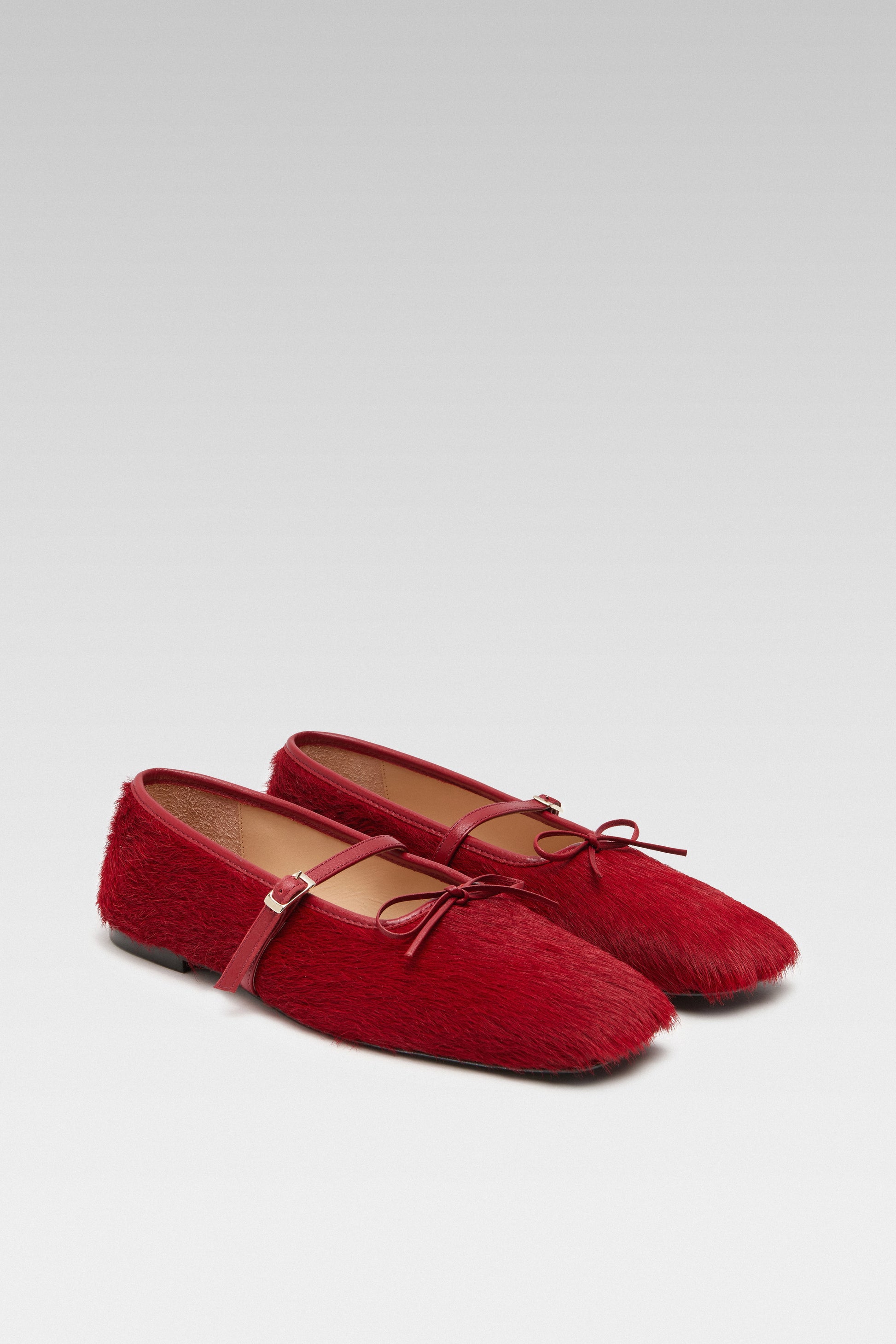 Three-quarter view of EDLA Mars red mary jane flats crafted from calf hair with a squared toe and bow detail.