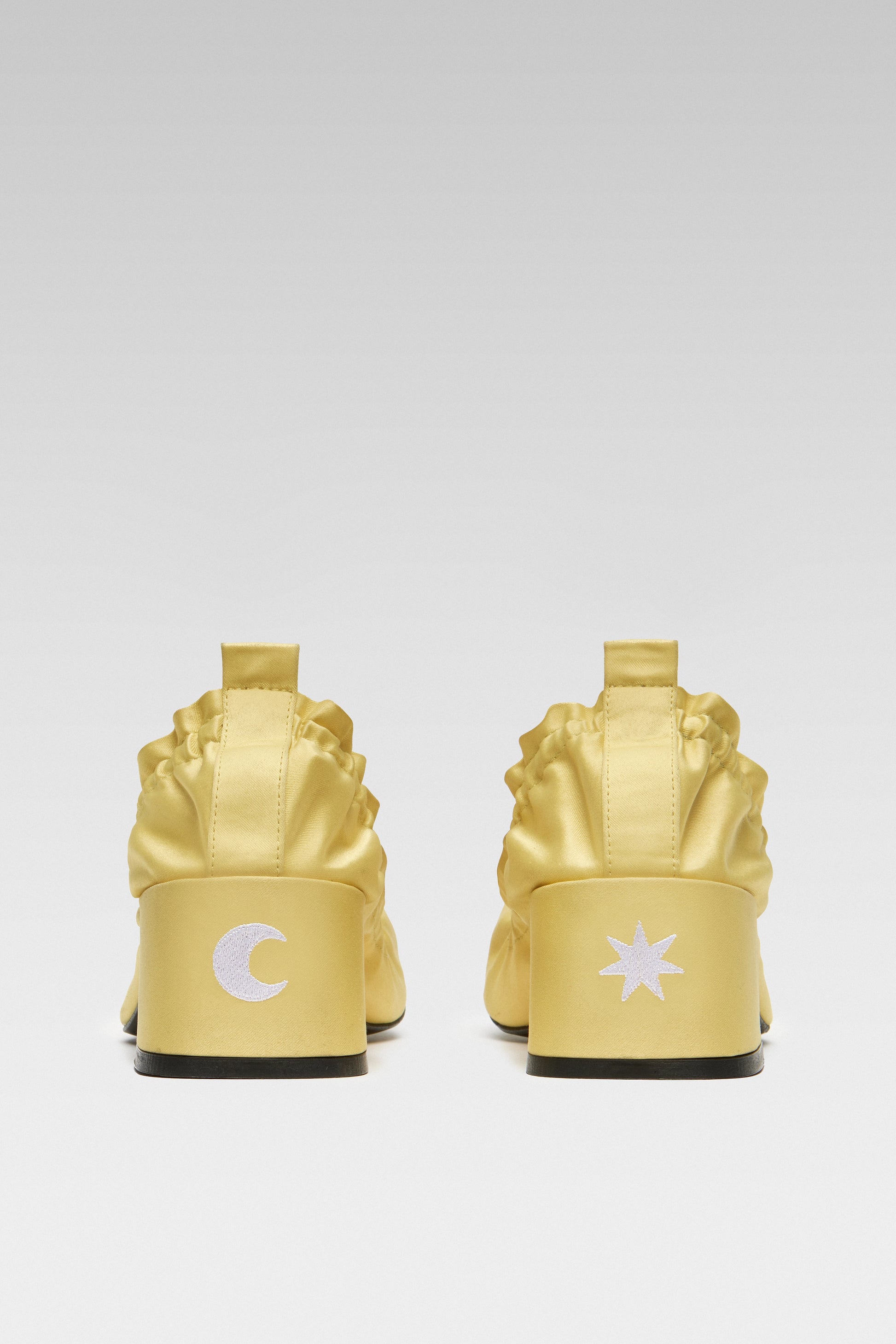 Back view of EDLA Mercury yellow kitten heels crafted from satin with star and moon white symbols at the back of the block heel.