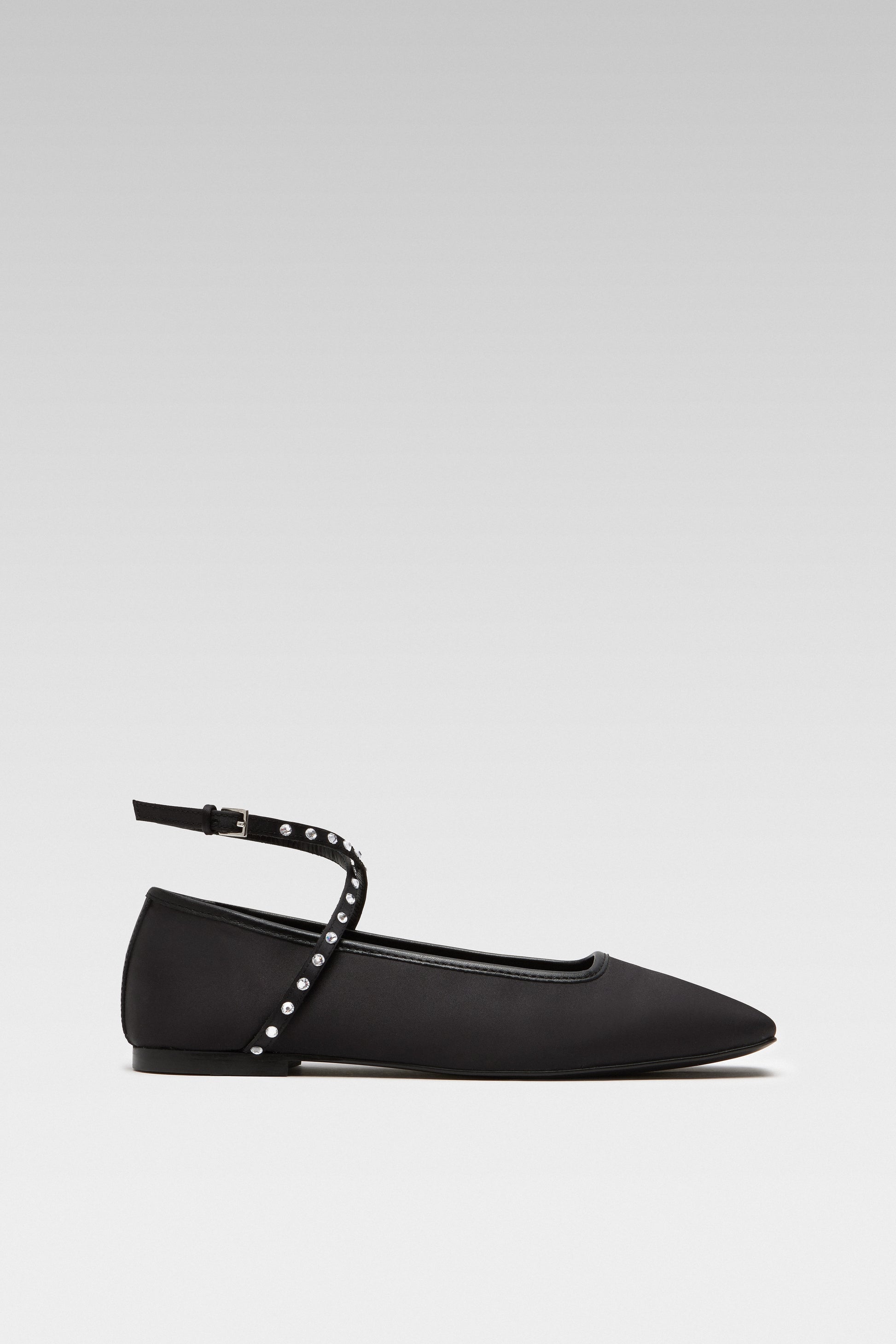 Side view of EDLA Saturn black ballet flats crafted from satin with ankle straps embellished with crystals.