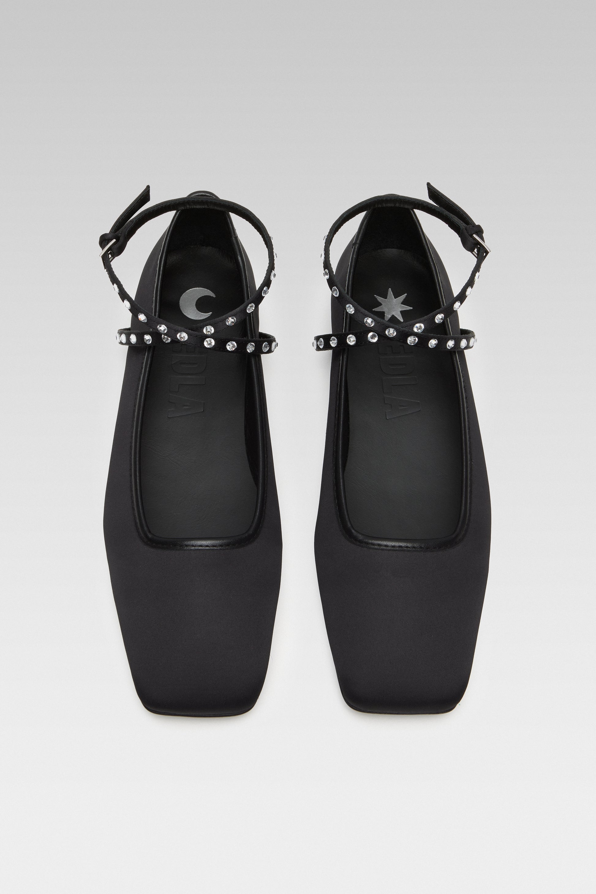 Top view of EDLA Saturn black ballet flats crafted from satin with a squared toe and ankle straps embellished with crystals.