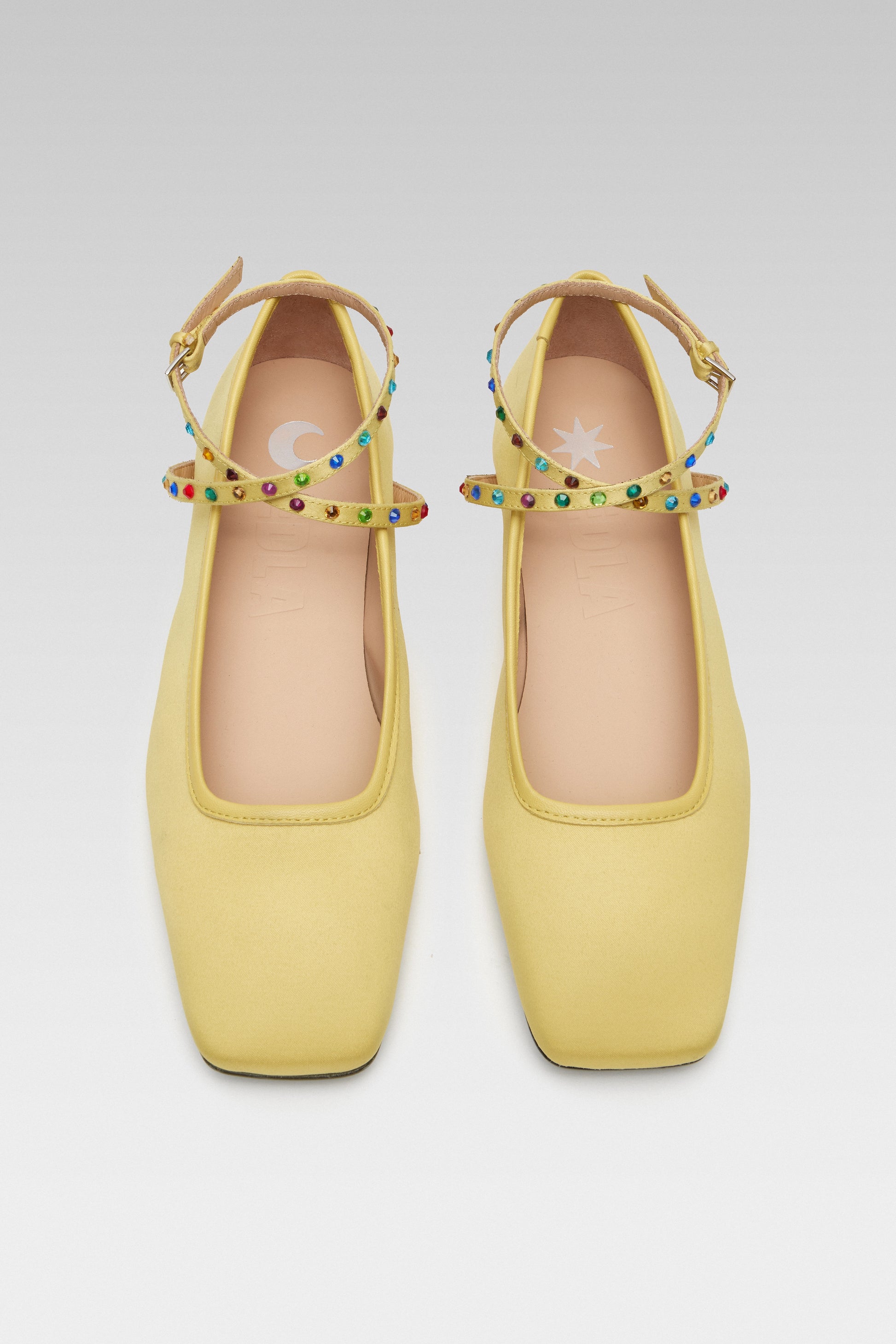 Top view of EDLA Saturn yellow ballet flats crafted from satin with a squared toe and ankle straps embellished with multicoloured crystals.