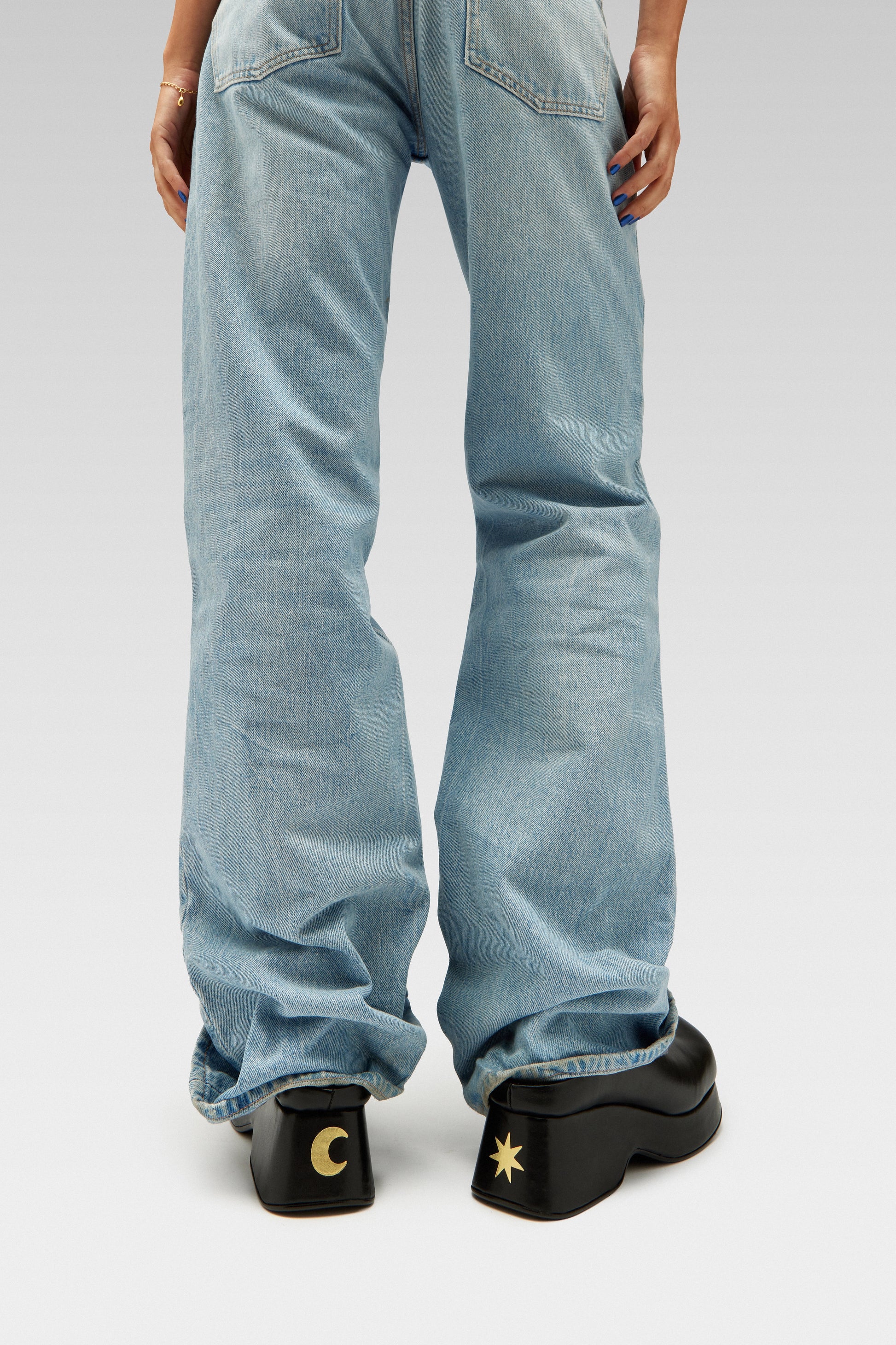 Model wearing blue jeans with EDLA Venus black mules featuring gold star and moon symbols at the back of the heel. A statement shoe to complete your Y2K outfit.